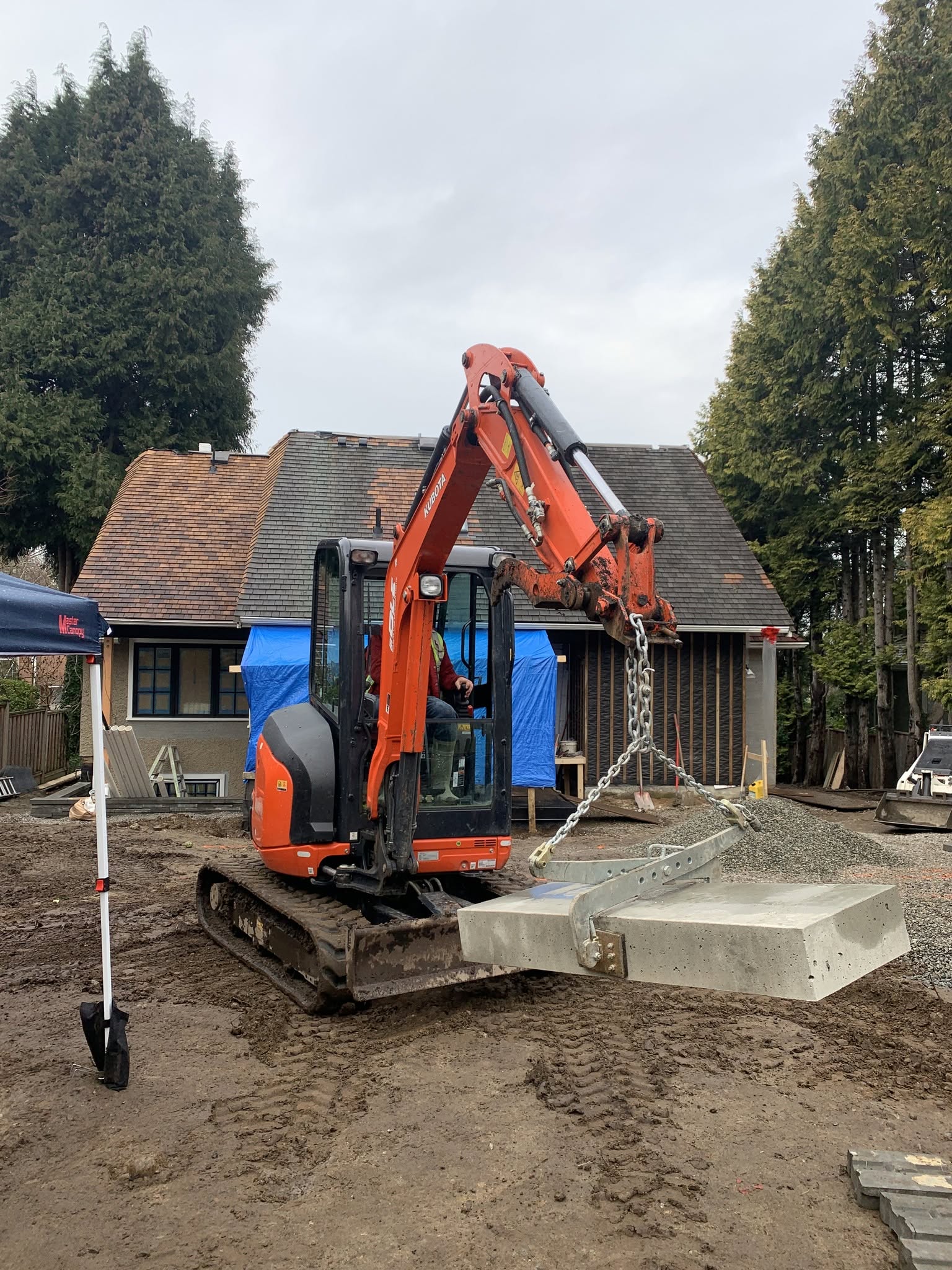 Second Generation Landscapes crew placing a concrete slab with a mini excavator